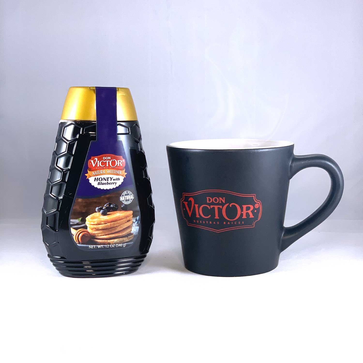 Bottle of Don Victor natural blueberry flavored honey beside a steaming mug of hot blueberry green tea with honey.